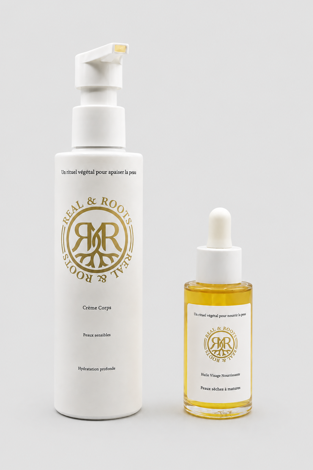 Flacon compte-gouttes d'huile visage nourrissante à côté de la crème corps, fond gris clair | Real & Roots